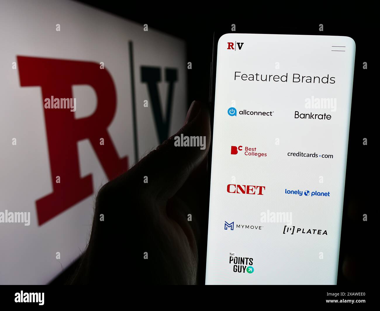 Person mit Mobiltelefon und Website des US-Medienunternehmens Red Ventures LLC vor dem Geschäftslogo. Konzentrieren Sie sich auf die Mitte des Telefondisplays. Stockfoto