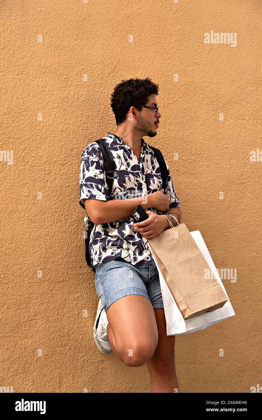 Städtereise: Junger Mann mit Brille und Einkaufstaschen. Urbane Mode, Pause, Lifestyle Stockfoto