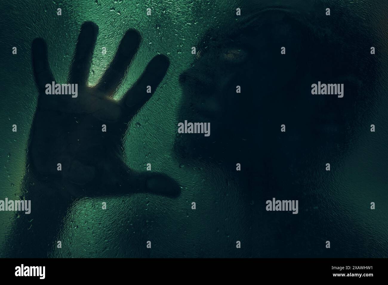 Horrorszene eines Mannes gegen nasses Glas. Hand vor dem Hintergrund einer nassen Glasbadewand. Getöntes Bild. Horror-Konzept Stockfoto