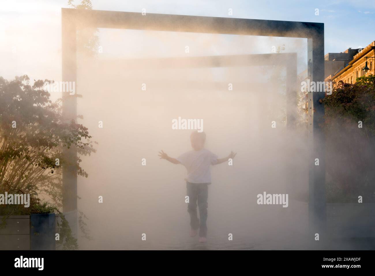 Hitzewelle. Kind spielt in einer Dampfwolke Stockfoto