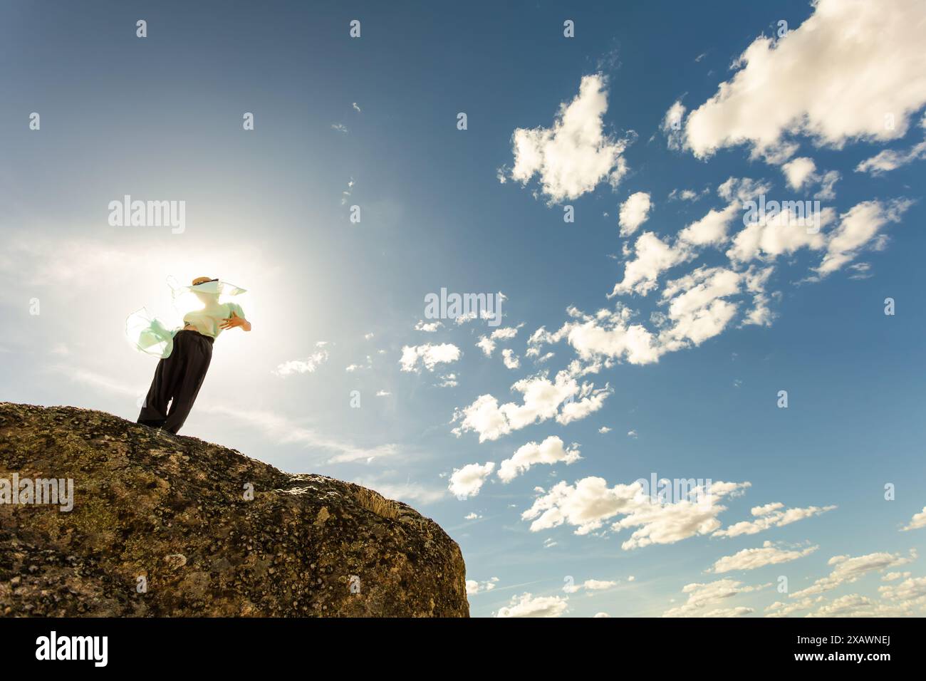 Frau mit Schal, Taschentuch, Kappe und Sonnenbrille bei Sonnenuntergang, Linsenfleck, Windwolken Hintergrund lächelndes Gesicht blauer Himmel, Tanz Stockfoto