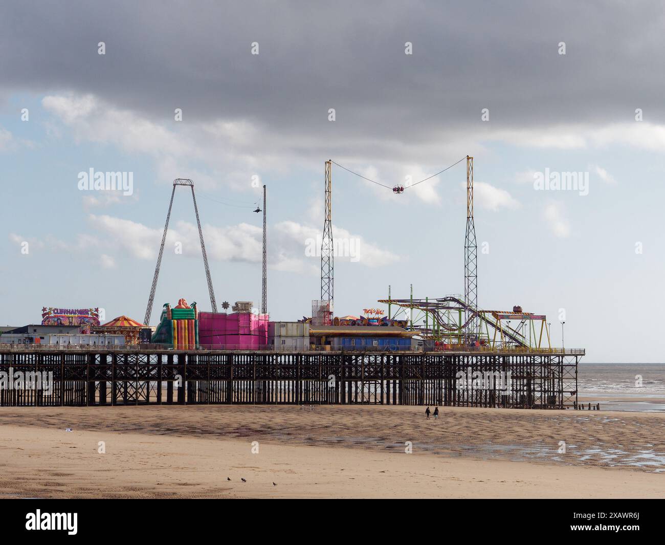 Touristen an einem Sandstrand am Amusement Park Pier in der Stadt Blackpool, Lancashire, England. Juni 2024 Stockfoto