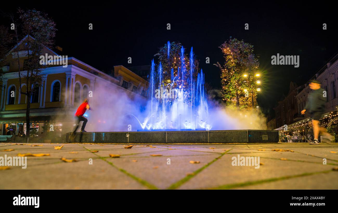 Kaunas, Litauen, 28. September 2023, farbenfroher beleuchteter Brunnen in der Innenstadt bei Nacht im magischen Licht neben Restaurants und Cafés Stockfoto