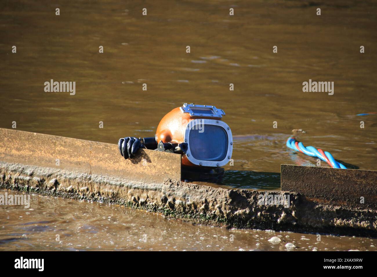 Der Helm eines Tauchers blickt aus einem Pool in einer Kläranlage Stockfoto
