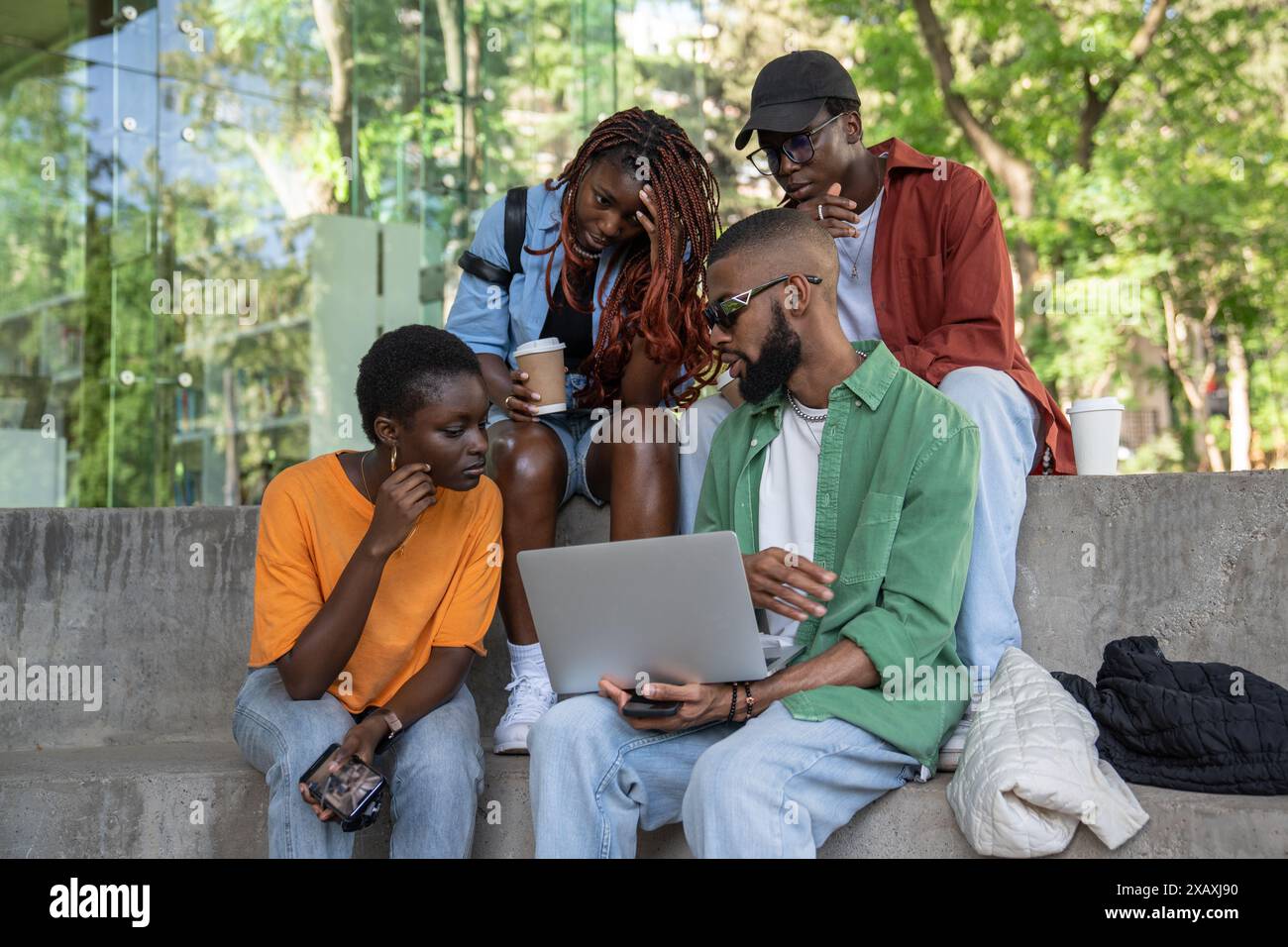 Freundliche Gesellschaft von schwarzen Studenten mit Laptop lernen im Park, Videos ansehen, schwierige Themen diskutieren Stockfoto