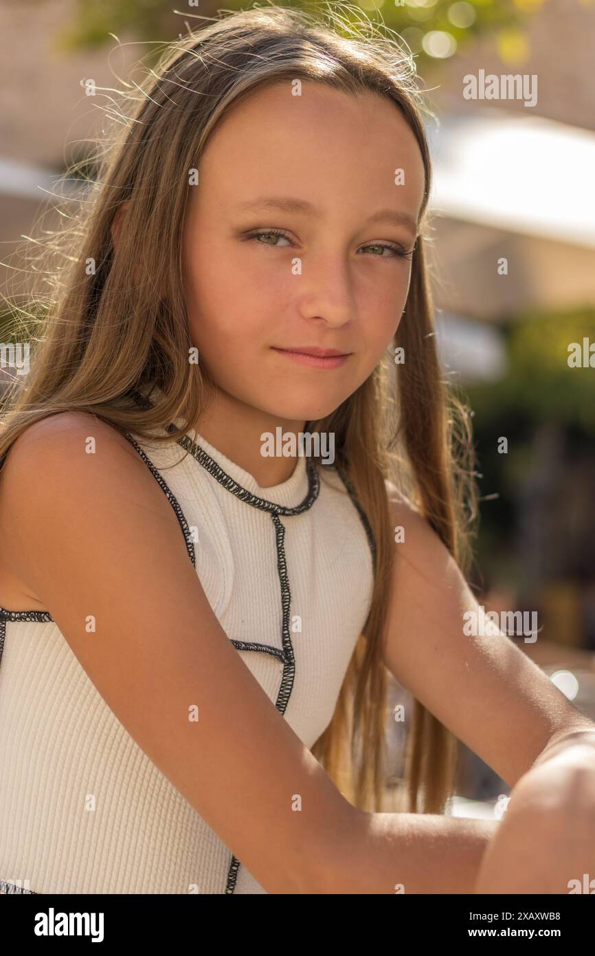 Das ist ein fesselndes Porträt eines schönen jungen Mädchens. Sie hat langes, fließendes blondes Haar und auffällige grüne Augen. Stockfoto