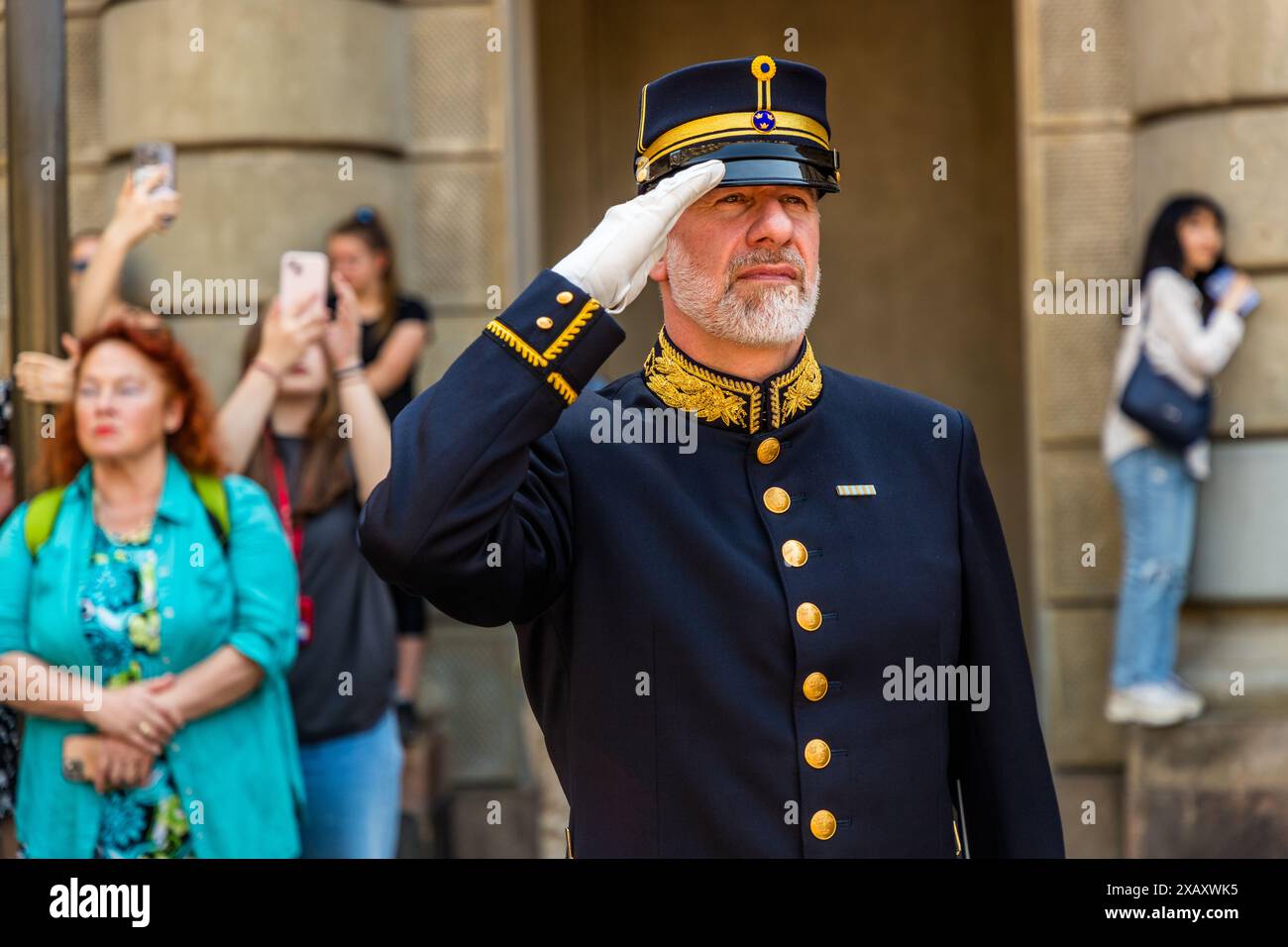 Der Dirigent der Kavallerie-Band grüßt während der Nationalhymne auf dem Schlossplatz. Ansonsten bleibt er unaufdringlich mitten im Publikum. Zeremonie der Kaisergarde im Königspalast von Stockholm. Wachwechsel vor dem schwedischen Königspalast in Stockholm mit musikalischer Begleitung der berittenen Band. Yttre borggården, Stockholm, Schweden Stockfoto