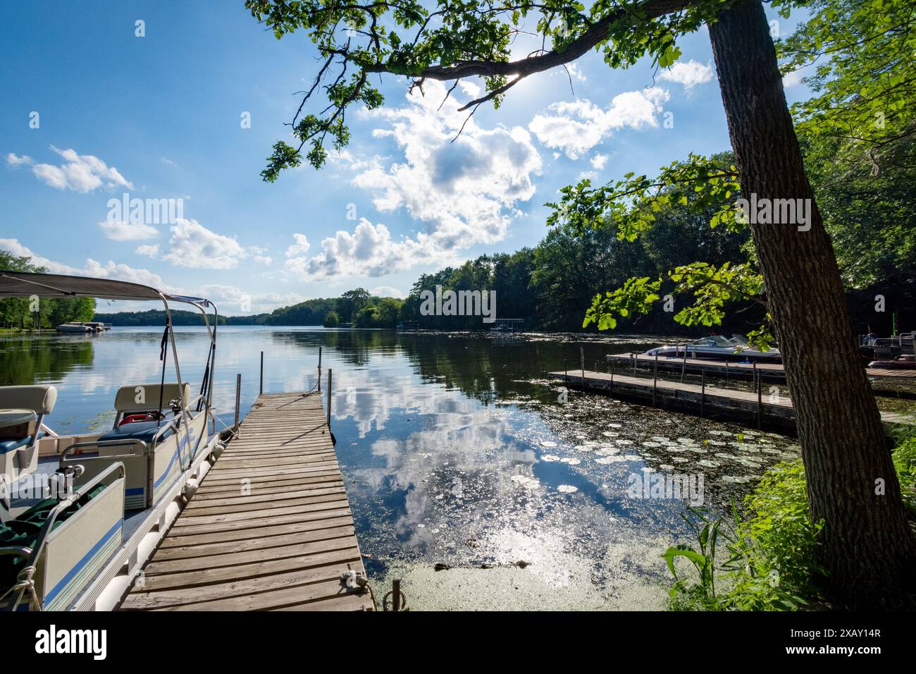 Am späten Nachmittag an einem ruhigen Tag vom Ufer aus mit einem Pontonboot an der Seite eines Piers auf einen See in Wisconsin. Stockfoto