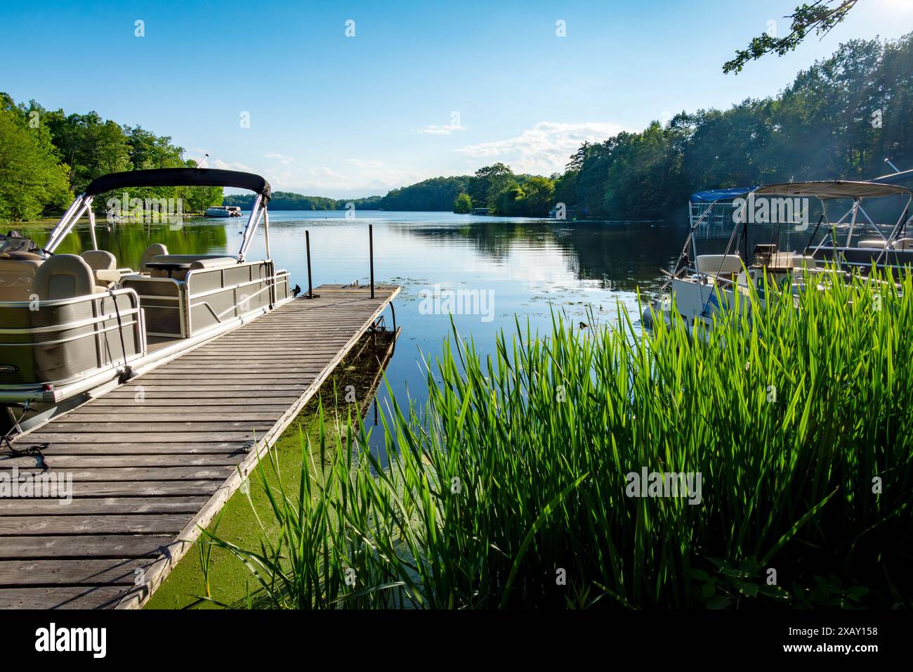 Am späten Nachmittag an einem ruhigen Tag vom Ufer aus mit einem Pontonboot an der Seite eines Piers auf einen See in Wisconsin. Stockfoto
