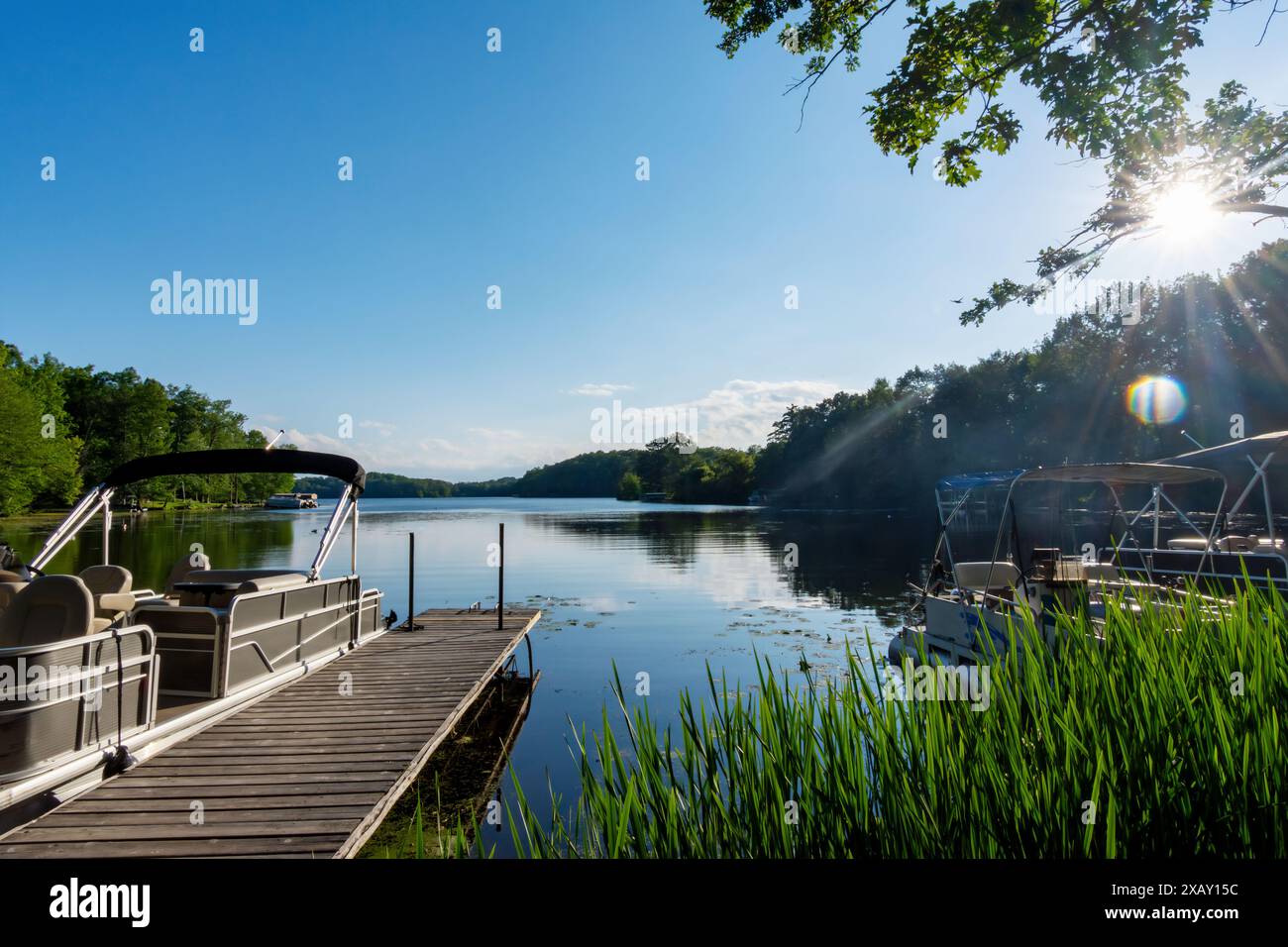 Am späten Nachmittag an einem ruhigen Tag vom Ufer aus mit einem Pontonboot an der Seite eines Piers auf einen See in Wisconsin. Stockfoto