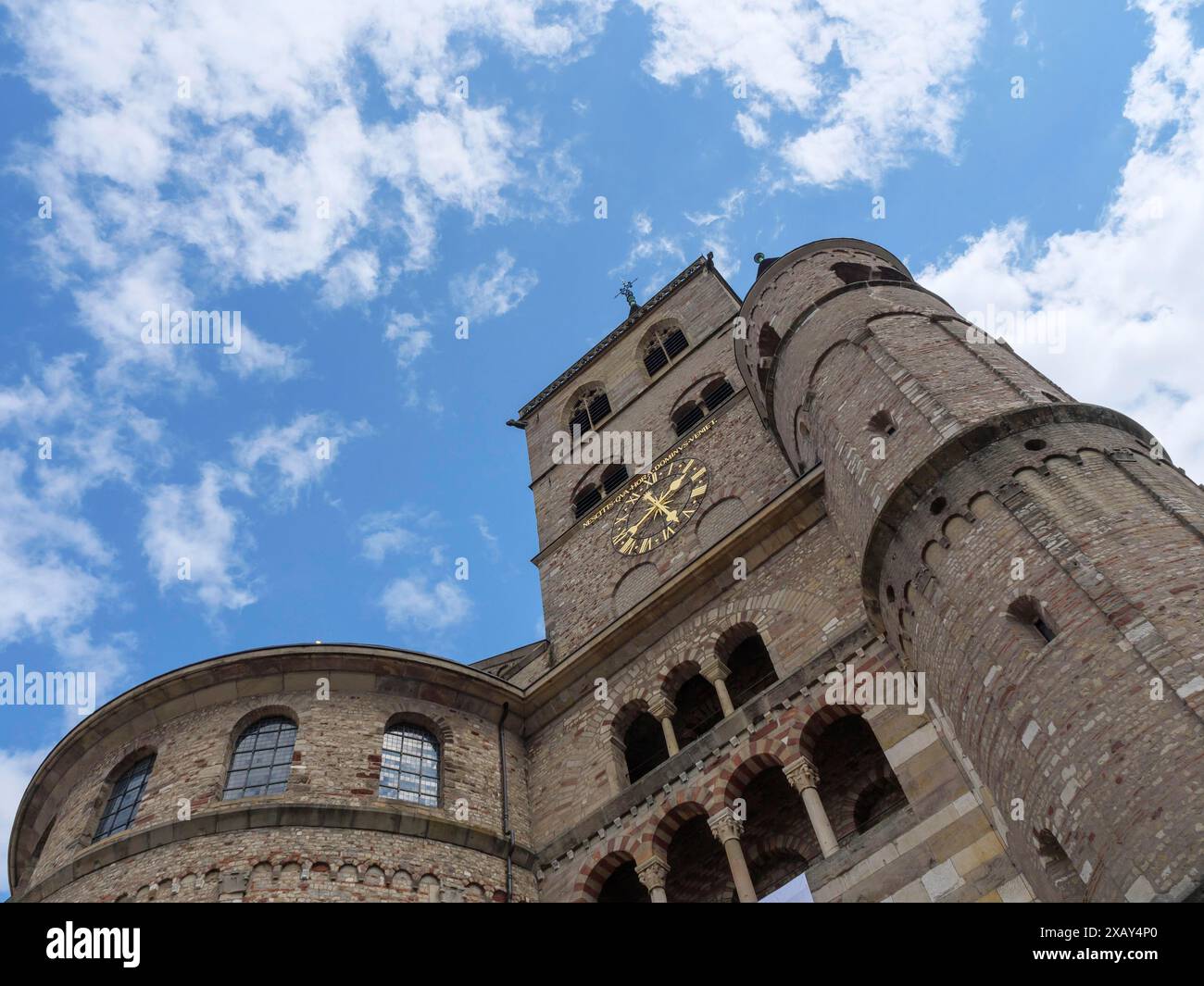 Perspektive eines gemauerten Kirchturms mit Uhr und gotischen Einflüssen vor bewölktem Himmel, trier, deutschland Stockfoto