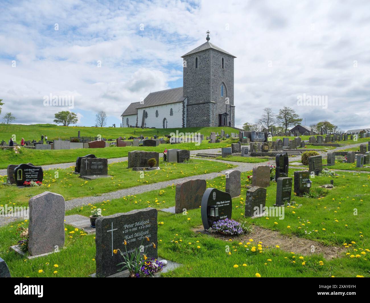 Friedhof mit alten Grabsteinen und einer Steinkirche im Hintergrund auf grünem Rasen, Haugesund, norwegen Stockfoto