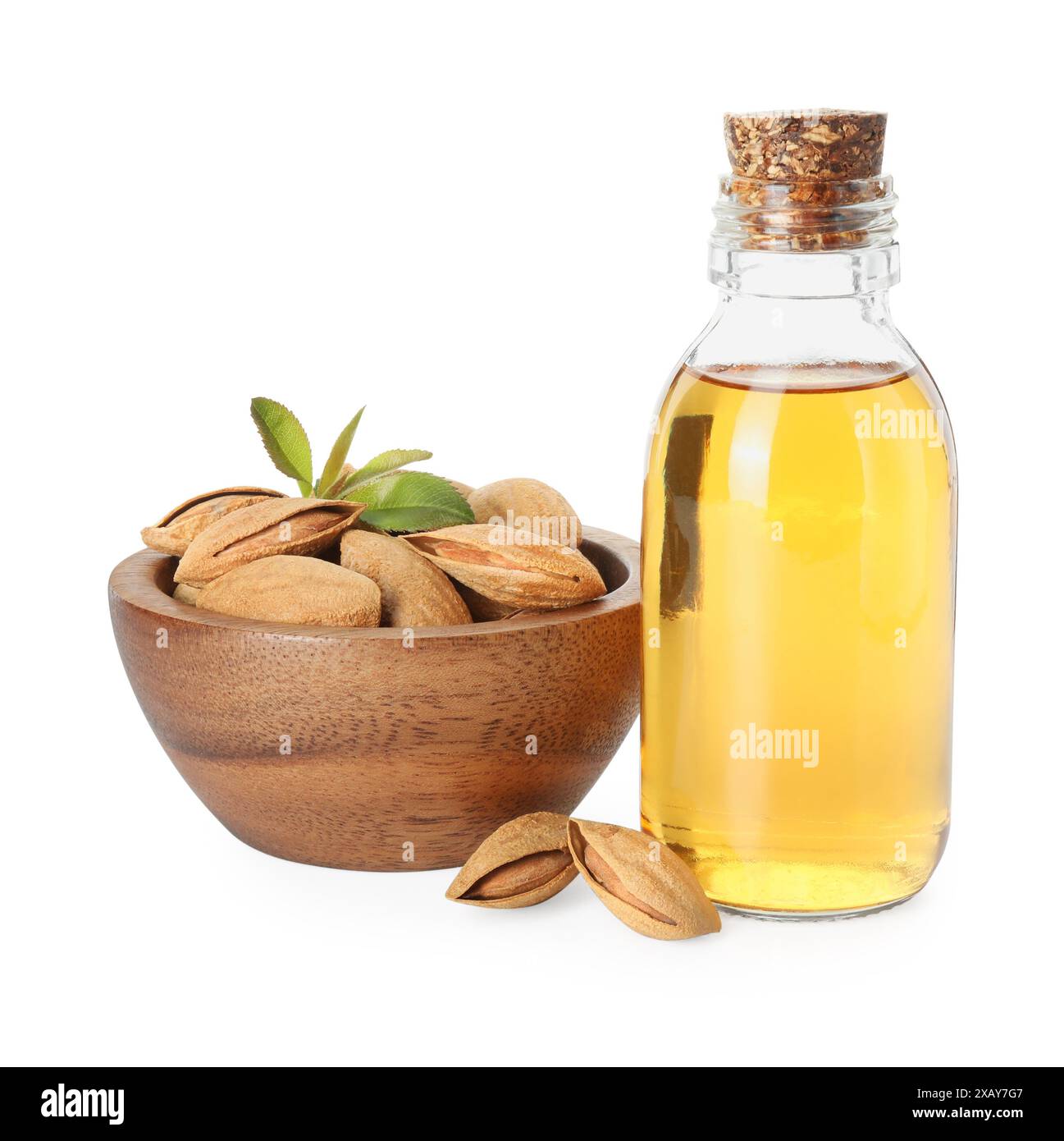 Flasche Mandelöl und frische Nüsse in Schüssel isoliert auf weiß Stockfoto