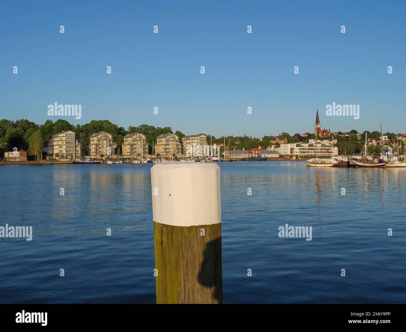 Ein Haufen im Vordergrund eines Hafens, moderne Gebäude, Boote und Kirche am Ufer bei Morgenlicht, Flensburg, Schleswig-Holstein, Deutschland Stockfoto