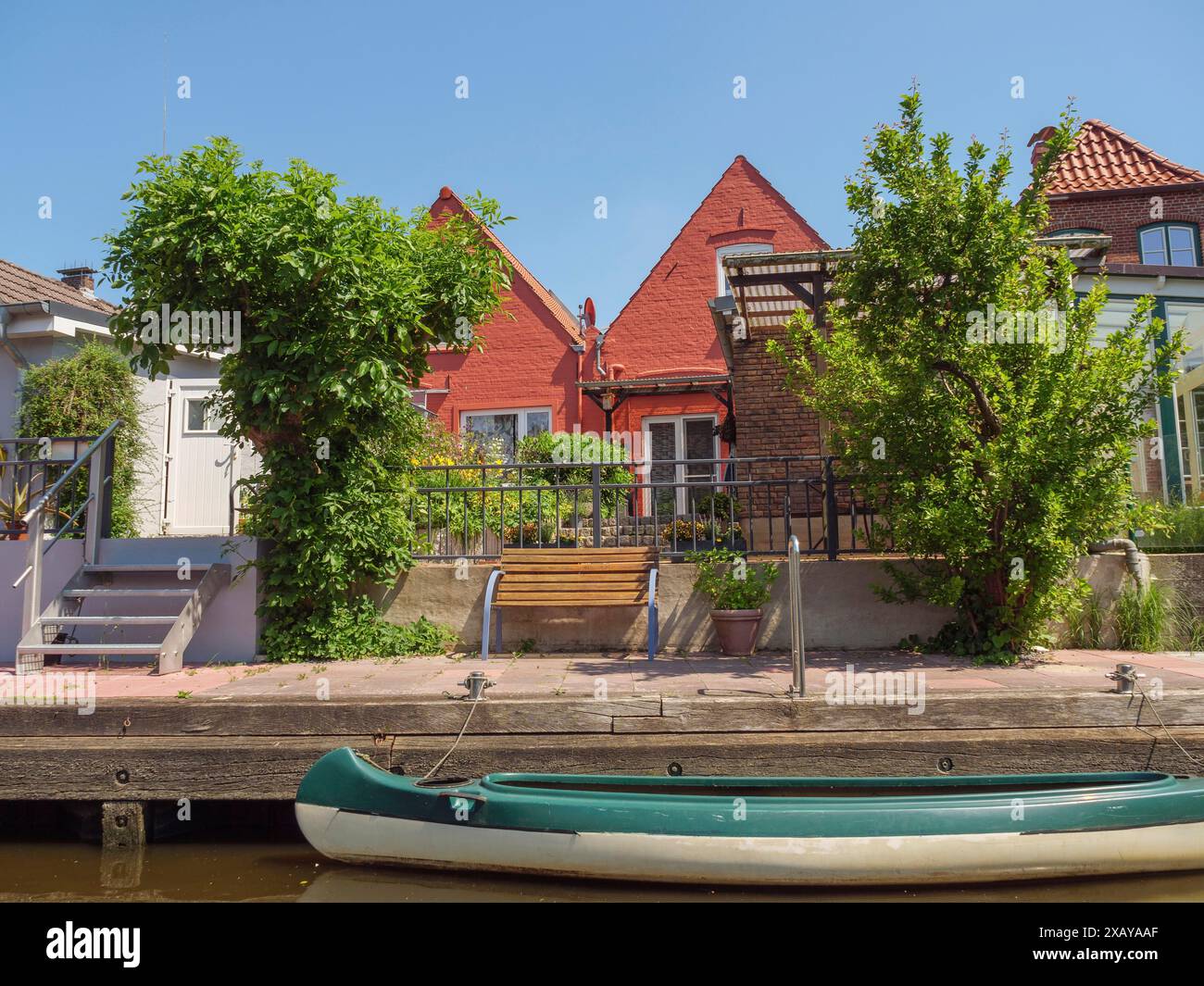 Haus am Kanal mit roten Dächern, umgeben von grünen Bäumen und einem Boot im Vordergrund, friedrichstadt, schleswig-holstein, deutschland Stockfoto