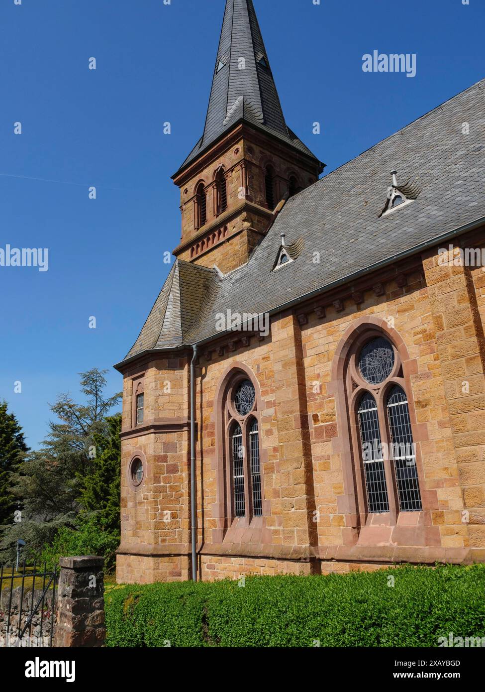 Seitenansicht einer Sandsteinkirche mit schönen Fenstern unter blauem Himmel an einem sonnigen Frühlingstag, Saarburg, Deutschland Stockfoto