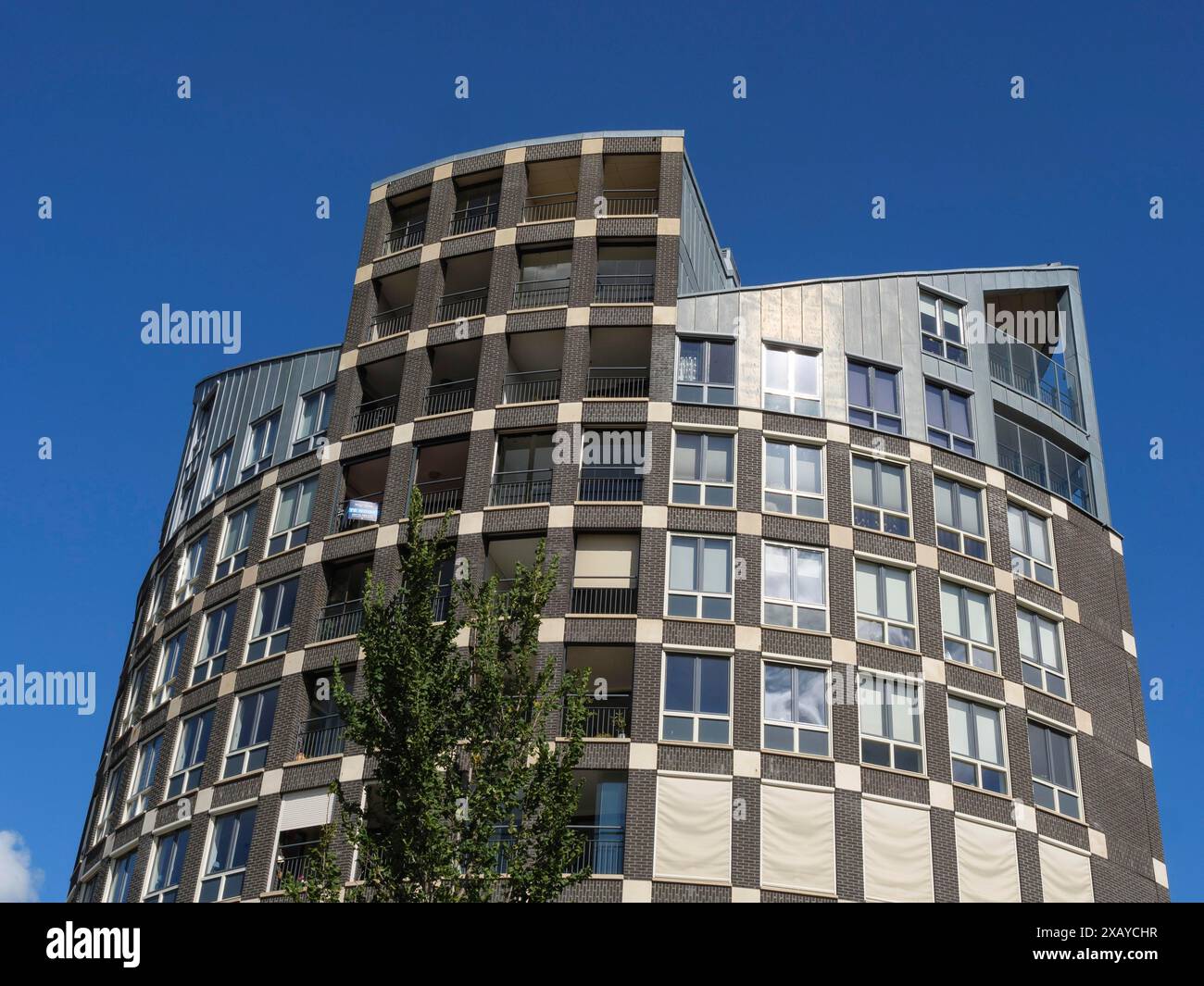 Detaillierter Blick auf einen modernen Wohnkomplex mit Balkonen und vielen Fenstern unter klarem Himmel, Doesburg, Niederlande Stockfoto