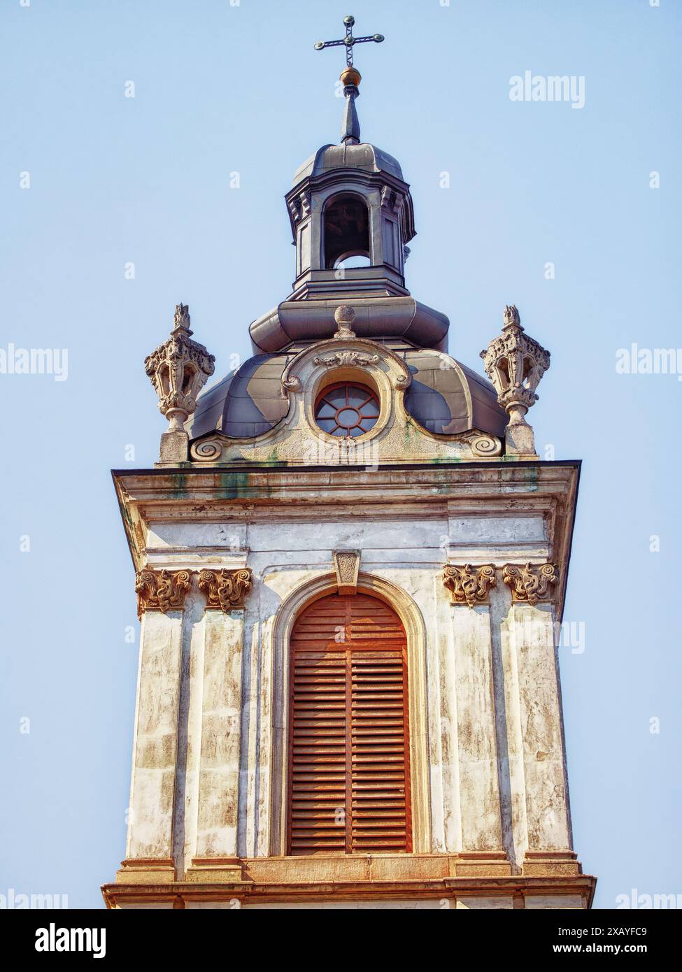 Kirchenkuppel und Kreuz. Kuppel und Kreuz auf einer barocken Kirche, heitere Himmelskulisse, die einen Ort der Anbetung anzeigt. Stockfoto
