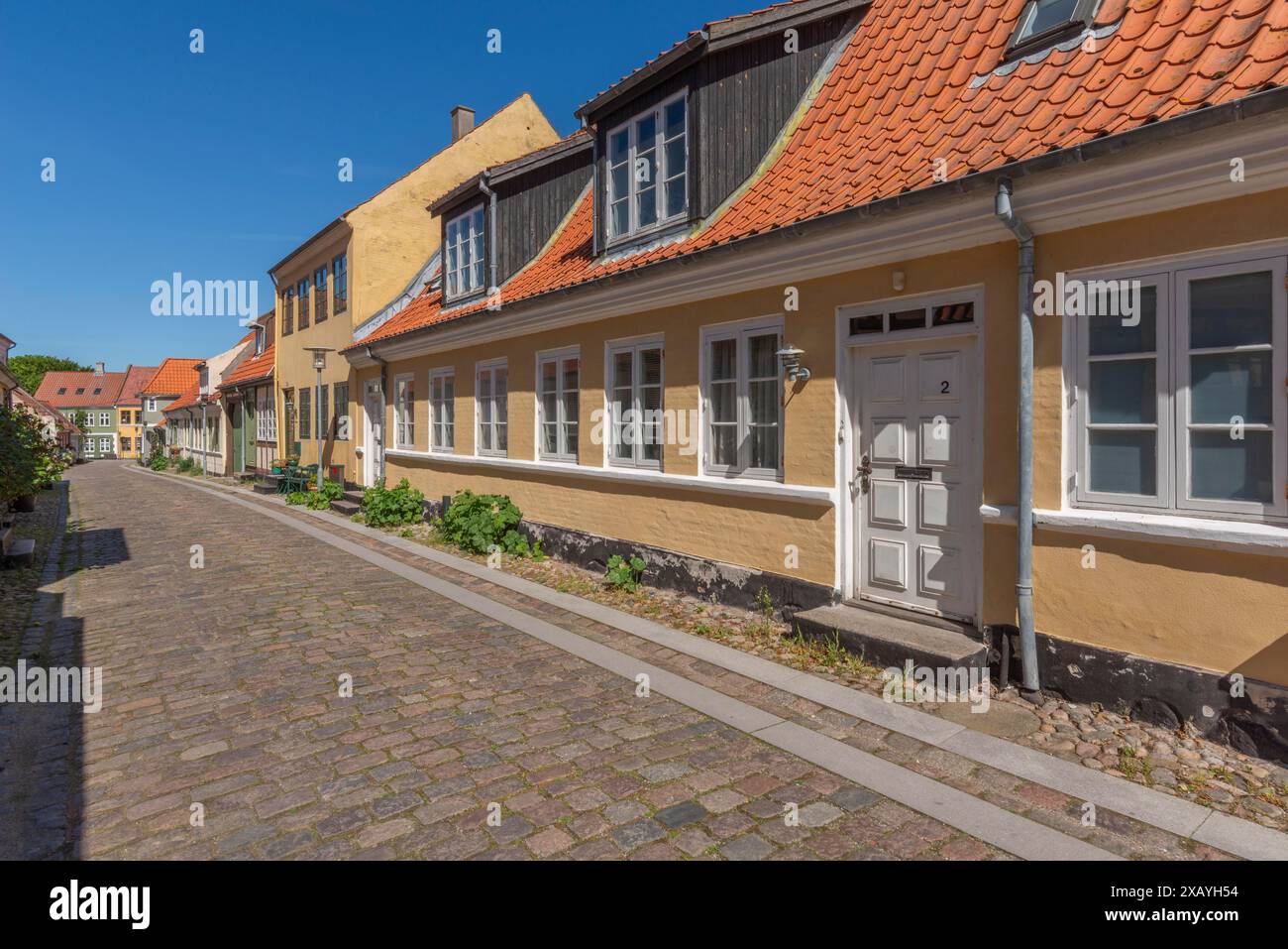 Altstadt von Rudkobing, renovierte Häuser, farbenfrohe Häuserreihe, Dachbalken, dekoratives Design, Pflanzen, verkehrsfreie Straße mit Kopfsteinpflaster Stockfoto