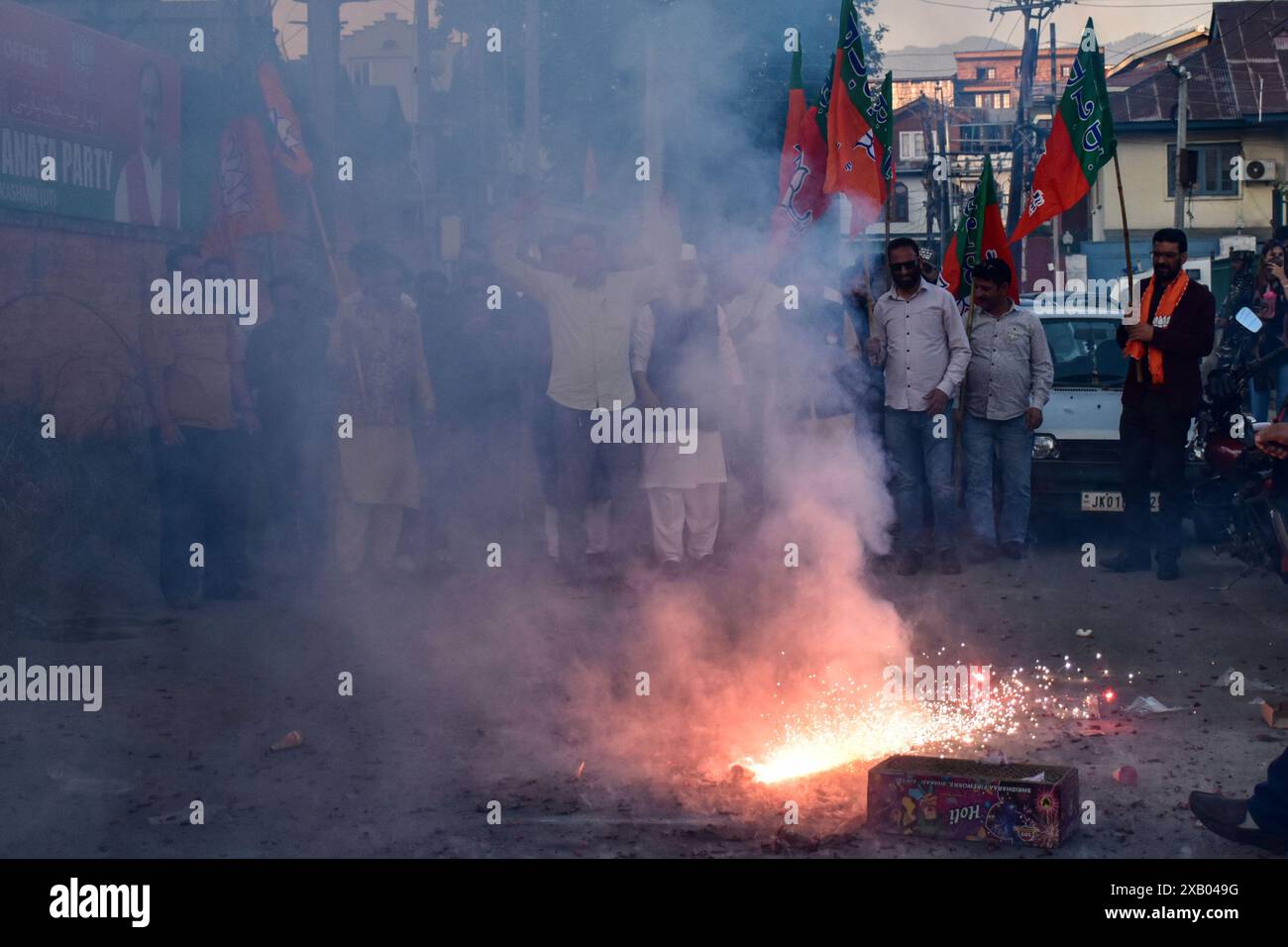 Srinagar, Indien. Juni 2024. Anhänger der Bharatiya Janata Party (BJP) halten Parteiflaggen und platzen Feuerwerkskörper, während sie Narendra Modis Vereidigungszeremonie als Premierminister für die dritte Amtszeit in Folge in Srinagar feiern. Narendra Modi, Anführerin der Hindu-Nationalist-Bharatiya-Janata-Partei (BJP), legte zum dritten Mal einen Eid als Premierminister Indiens ab. Die Zeremonie fand in Rashtrapati Bhavan in der indischen Hauptstadt Neu-Delhi statt. Der 73-jährige Führer ist nur der zweite indische Premierminister, der die Macht für eine dritte Amtszeit behält. Quelle: SOPA Images Limited/Alamy Live News Stockfoto