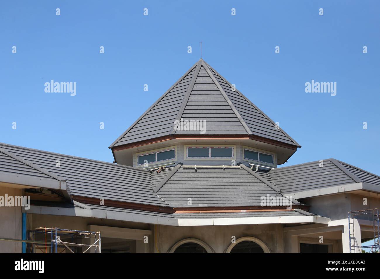 Giebeldach und Winkel des Dachs eines Hauses, das tagsüber im Bau ist, mit einem hellblauen Himmel. Stockfoto