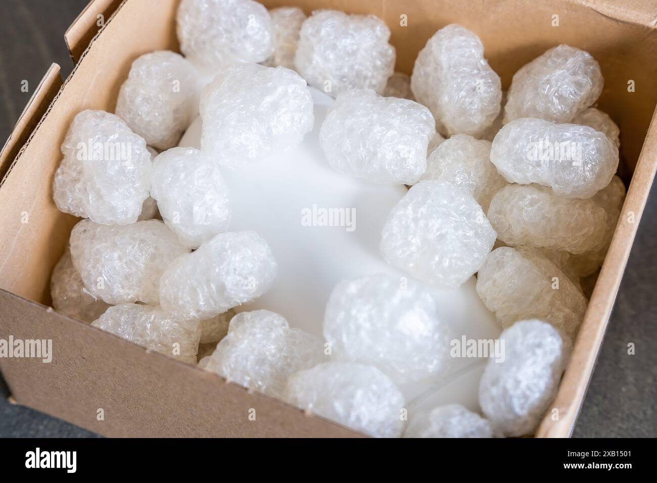 Umweltfreundliche Verpackung von Paketen und weißem biologisch abbaubarem Füllstoff. Die Box ist mit einem Füllstoff für die Umwelt gefüllt. Lieferung von Waren, Paketen, Lieferung Stockfoto