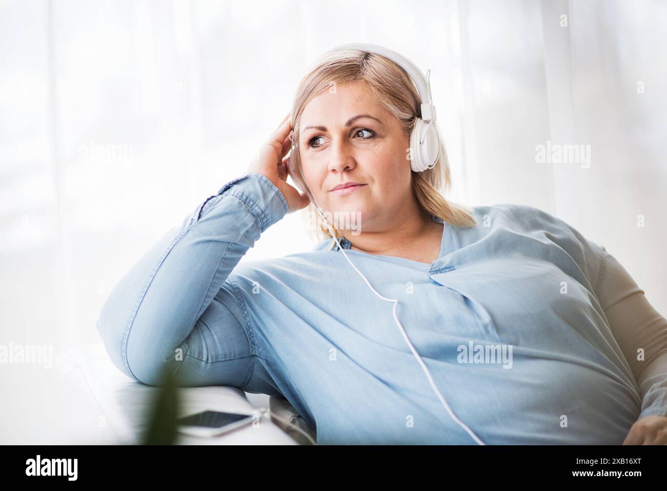 Porträt einer schönen jungen übergewichtigen Frau zu Hause, Musik über Kopfhörer hören, vermitteln, einen friedlichen Wochenendtag genießen. Stockfoto