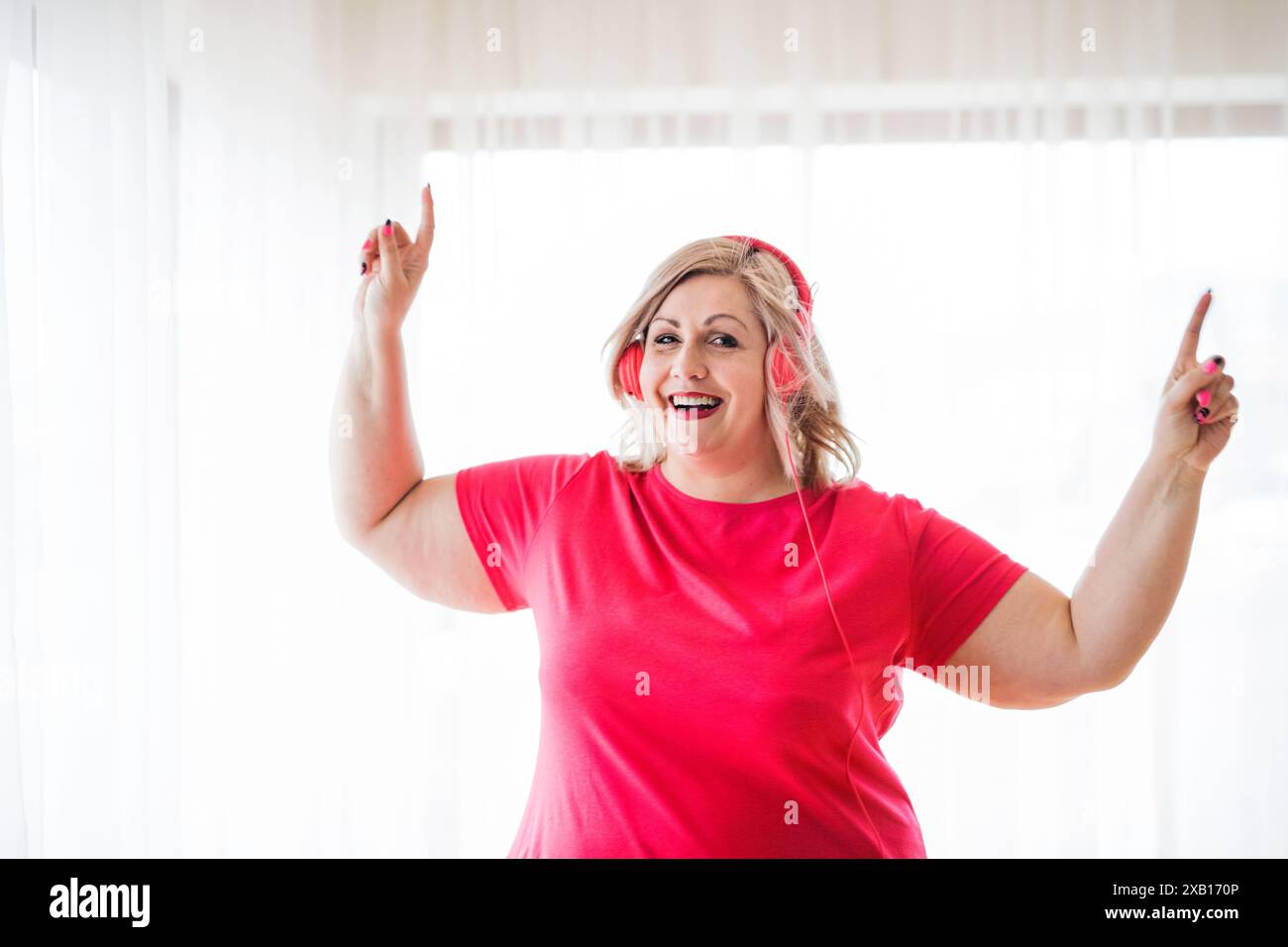 Porträt einer schönen jungen übergewichtigen Frau zu Hause, Musik über Kopfhörer hören, Spaß haben. Stockfoto