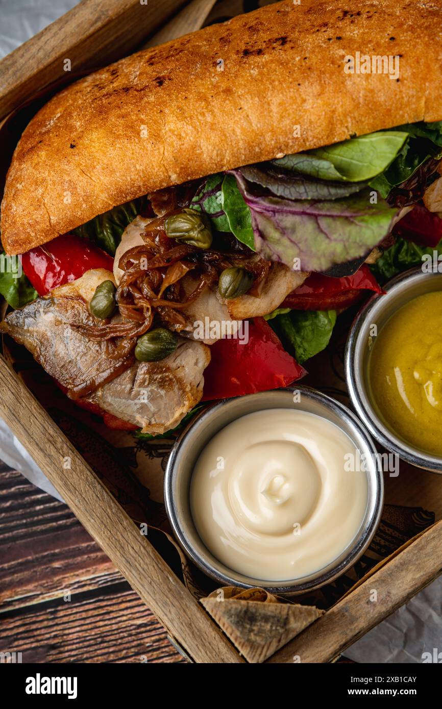 Steak-Sandwich mit Saucen und Pommes frites auf Holztisch Stockfoto