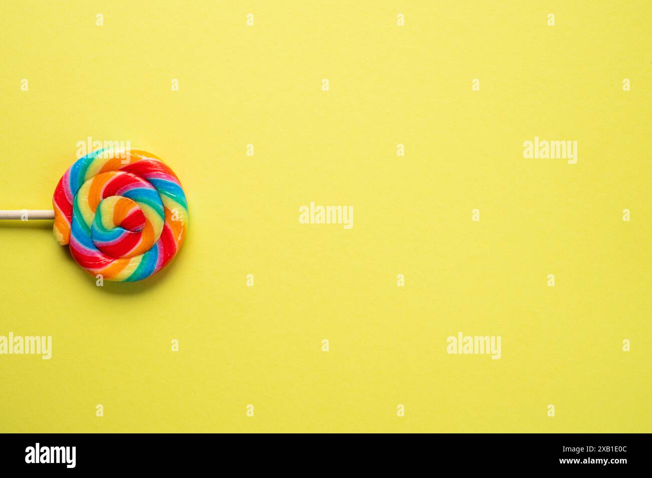 Regenbogenfarbene Lollypop auf einem hellgelben Hintergrund Stockfoto