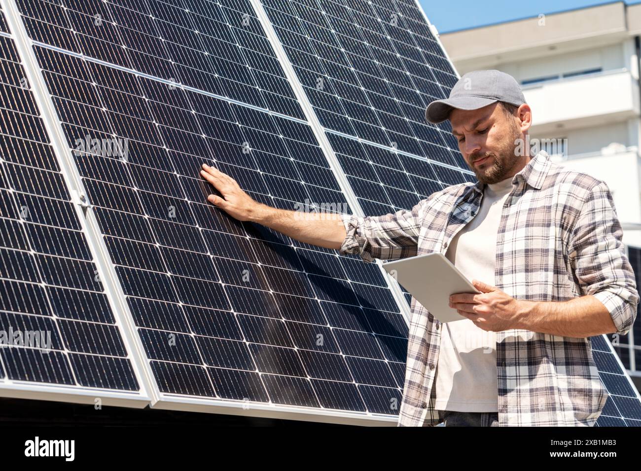 Der Techniker der Solaranlage überprüft die Wartung der Solarpaneele in der Stadt, berührt die Oberfläche des Solarpaneels und betrachtet das digitale Tablet. Stockfoto