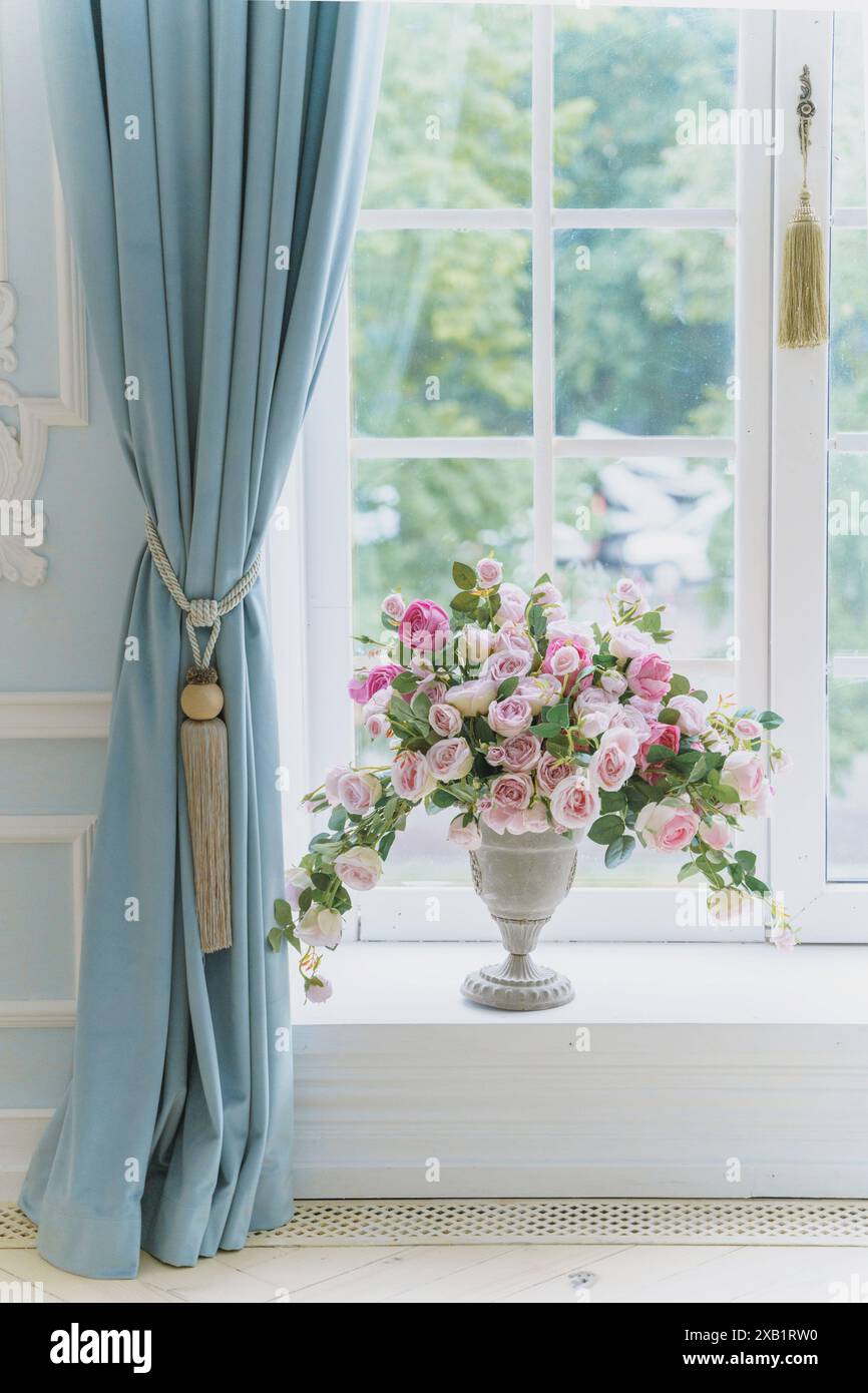 Ein Strauß frischer rosafarbener Blumen in einer antiken Vase in luxuriöser Innenausstattung auf einer Fensterbank. Stockfoto