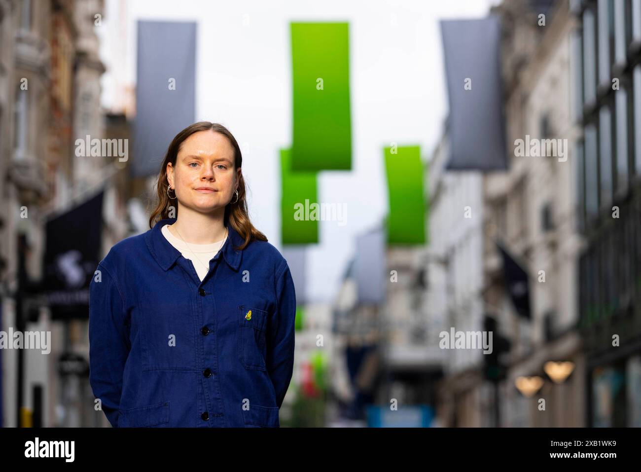 Die Künstlerin und aktuelle Studentin an den RA Schools, Lizzie Munn bei der Enthüllung ihrer Sammlung neuer Flaggen mit dem Titel „The Sun Speaks“ in der Bond Street in London, die von Art of London und Art in Mayfair in Zusammenarbeit mit der Royal Academy of Arts in Auftrag gegeben wurde. Bilddatum: Montag, 10. Juni 2024. Stockfoto