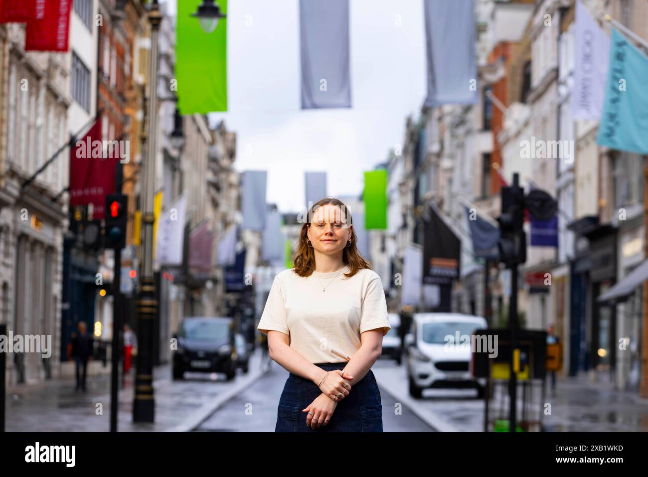 Die Künstlerin und aktuelle Studentin an den RA Schools, Lizzie Munn bei der Enthüllung ihrer Sammlung neuer Flaggen mit dem Titel „The Sun Speaks“ in der Bond Street in London, die von Art of London und Art in Mayfair in Zusammenarbeit mit der Royal Academy of Arts in Auftrag gegeben wurde. Bilddatum: Montag, 10. Juni 2024. Stockfoto