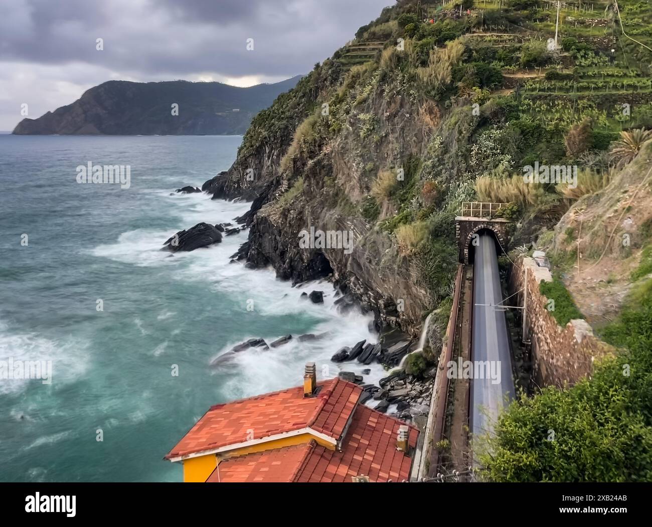 Lange Belichtungsunschärfe des Zuges, der durch einen Tunnel am Meer in Italien fährt. Stockfoto