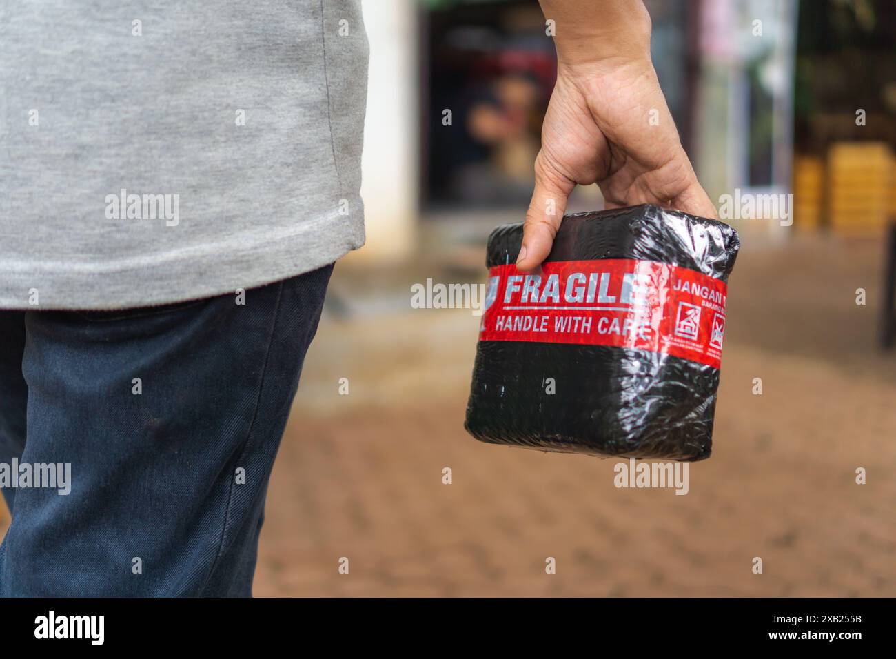 Einkäufe nach Hause, Kurier, der das Bestellpaket mit einem Aufkleber für zerbrechliche Artikel zustellt Stockfoto