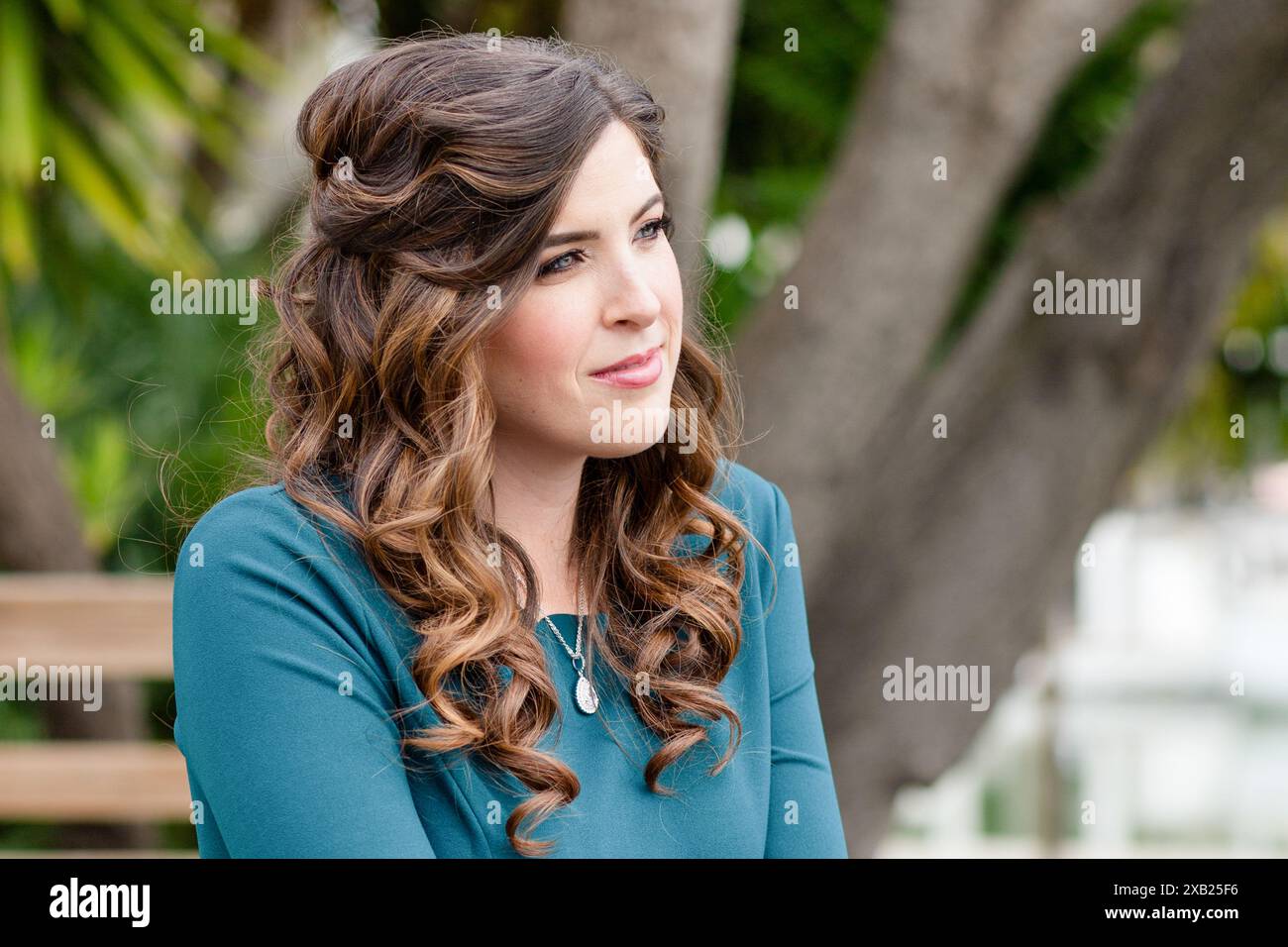 Frauen, die in die Ferne blicken, mit lockigem Haar und einem sanften Lächeln Stockfoto