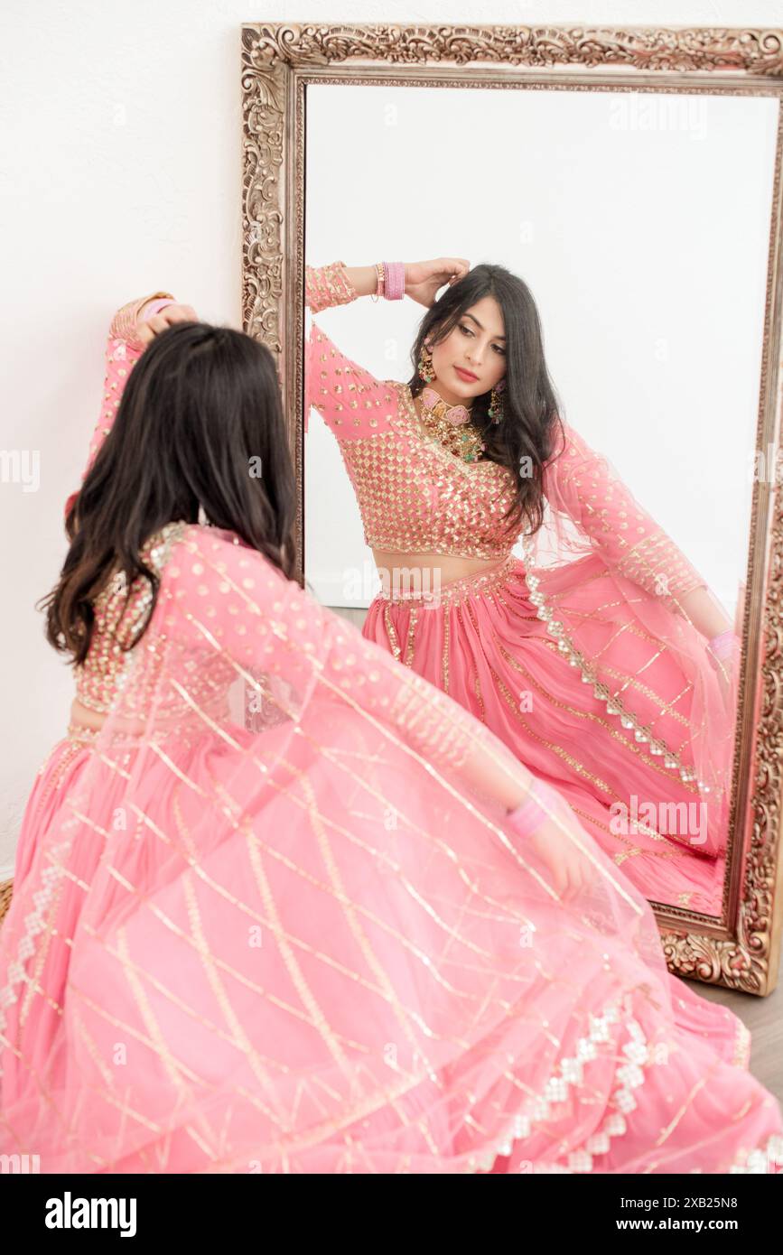 Frauen, die in den Spiegel schauen, tragen einen rosa Saree Stockfoto