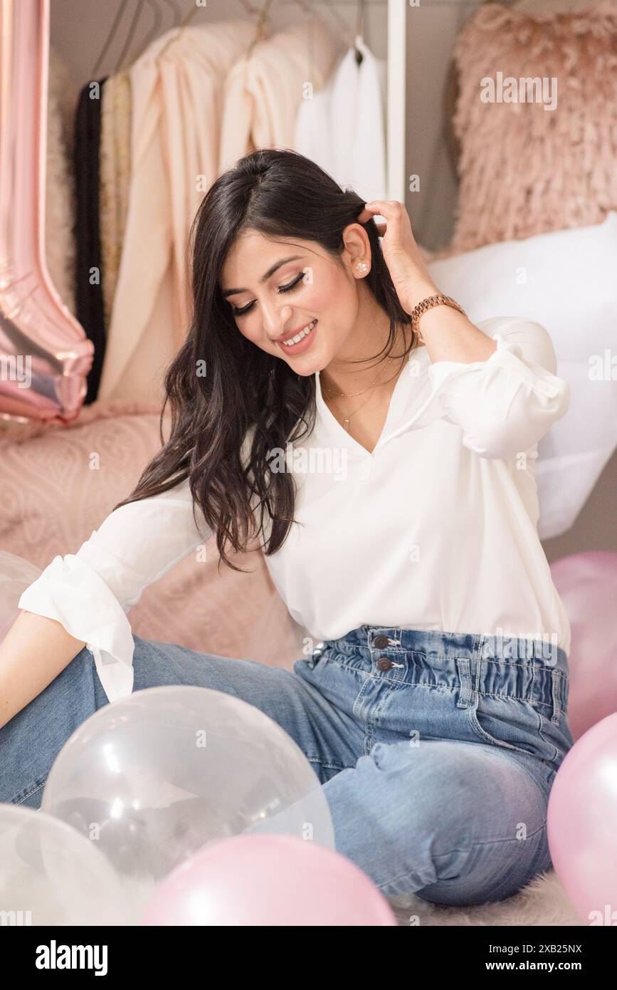 Frauen, die auf dem Boden sitzen, umgeben von Ballons, die nach unten schauen Stockfoto