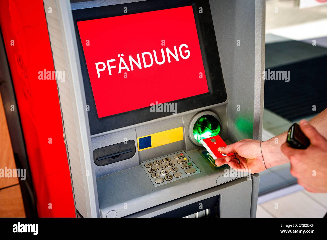 Juni 2024: Geldautomat mit dem Etikett: Krampfanfall. Ein Mann legt eine EC-Karte in den Geldautomaten ein, während die Warnung angezeigt wird. FOTOMONTAGE *** Bankautomat mit Aufschrift: Pfändung. Ein Mann steckt eine EC-Karte in den Geldautomat, während die Warnung angezeigt wird. FOTOMONTAGE Stockfoto