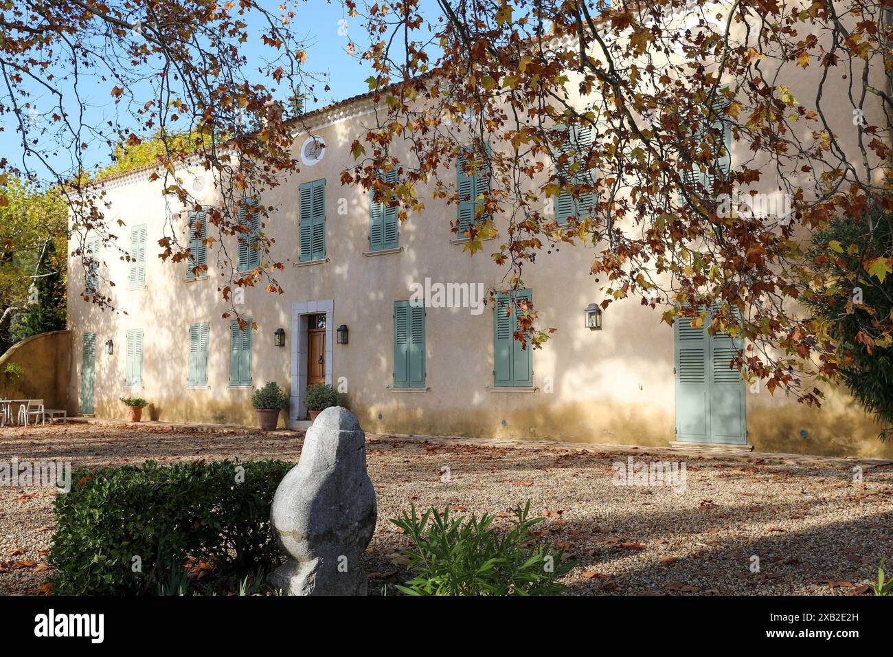 Ein elegantes Haus mit grünen Fensterläden, eingebettet in Südfrankreich. Das Haus ist von einem charmanten Garten mit Herbstlaub umgeben, wodurch ein pict entsteht Stockfoto