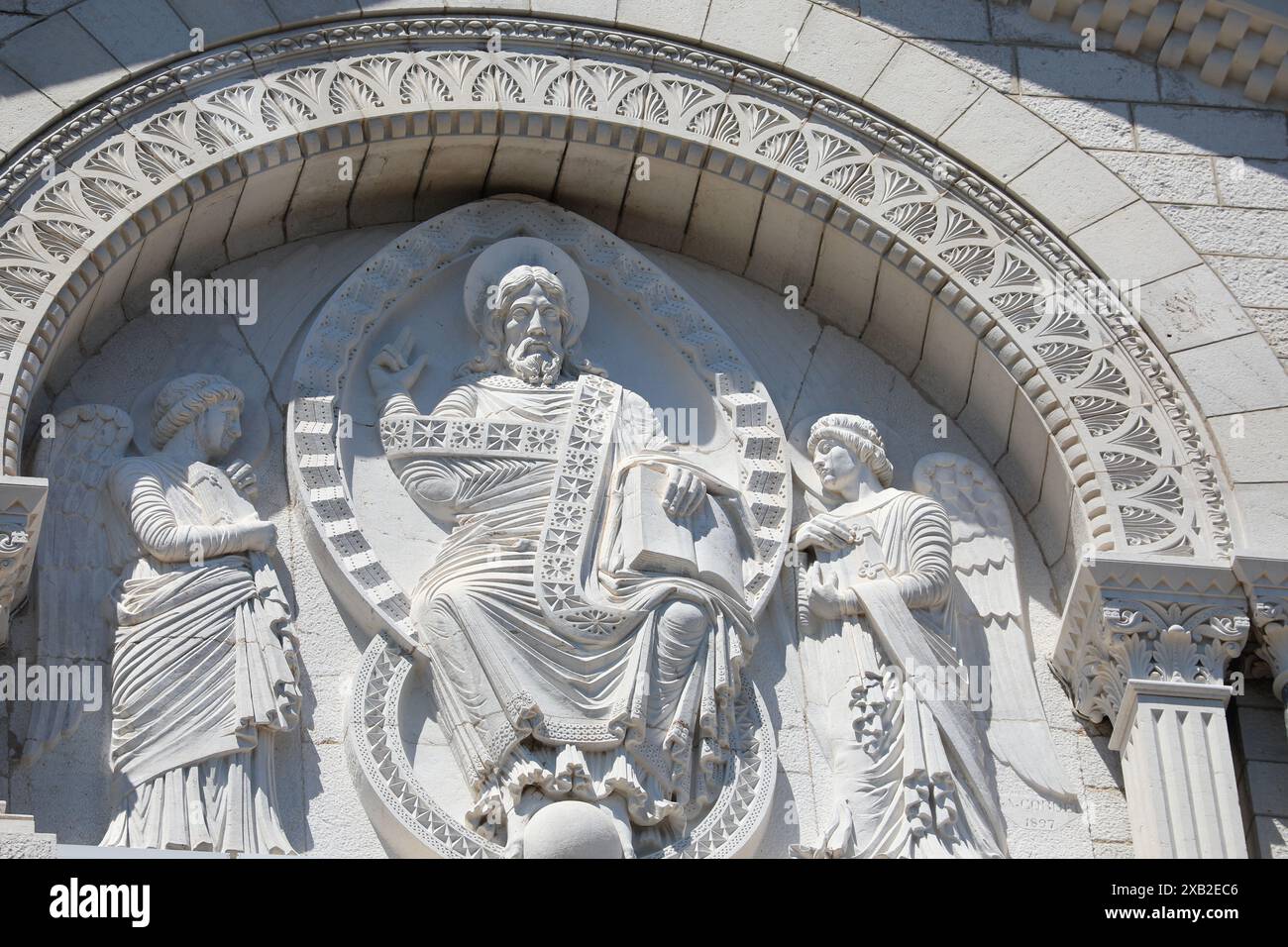 Ein kompliziertes Steinrelief auf der Kathedrale von Monaco, das religiöse Figuren mit raffinierten Details darstellt. Die Handwerkskunst und Kunstfertigkeit unterstreichen den guten Tag Stockfoto