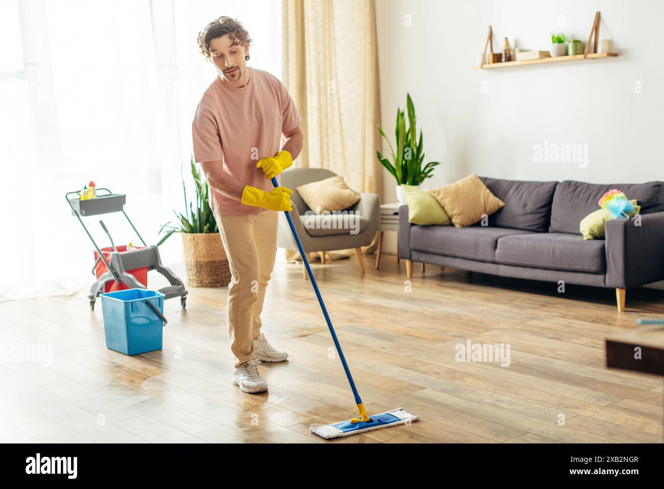 Ein Mann in Heimkleidung wischt anmutig den Boden. Stockfoto