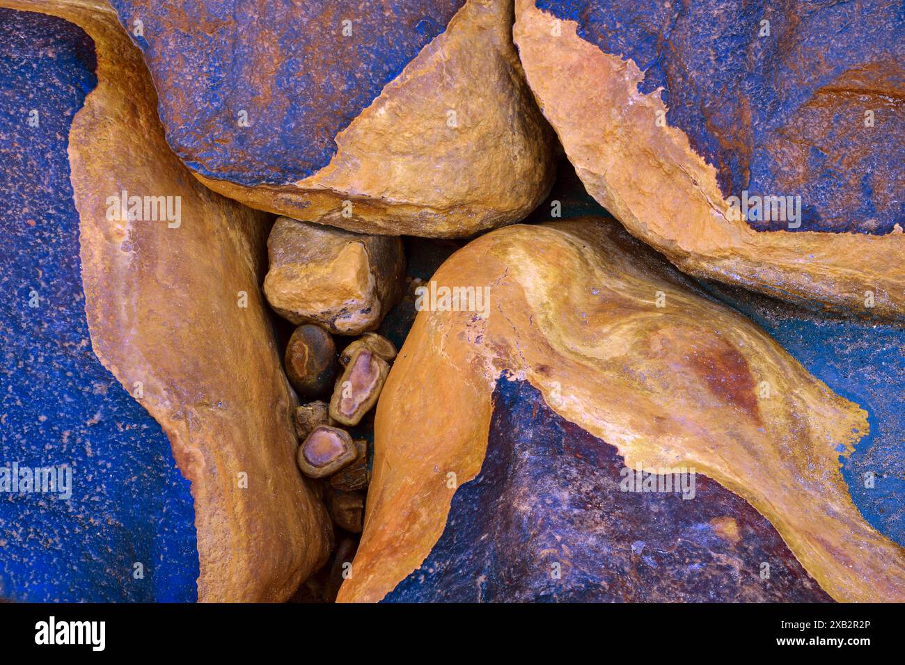 Nahaufnahme natürlicher Felsen mit leuchtend blauen und rostigen Texturen, ideal für Hintergründe oder abstrakte Kunstthemen Stockfoto