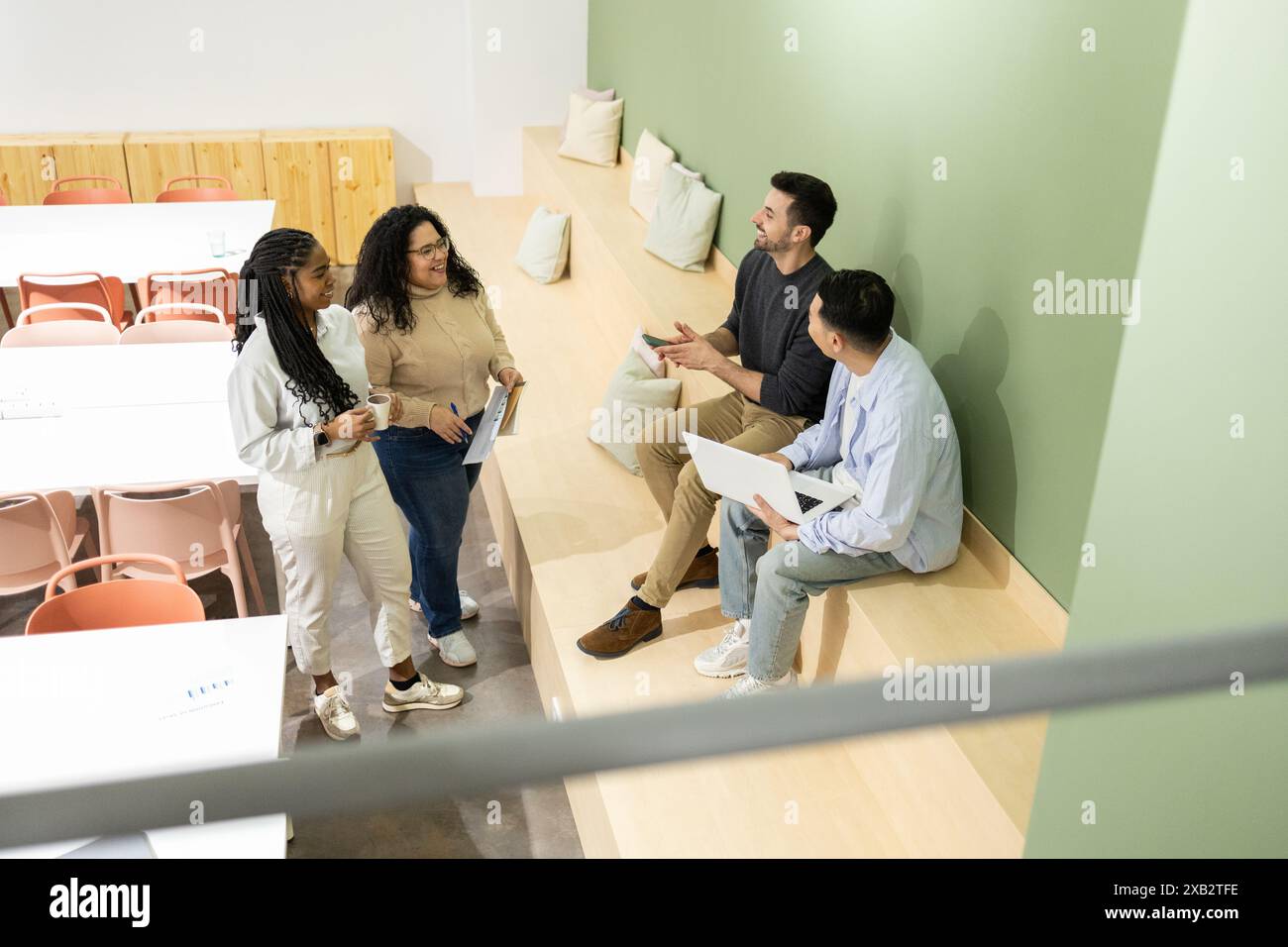 Ein Team junger, vielfältiger Freunde führt in einer hellen, modernen Coworking-Umgebung eine gemeinsame Diskussion durch, in der Teamarbeit und cre vorgestellt werden Stockfoto