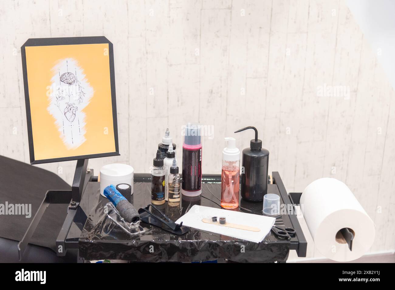 Ein anonymer Arbeitsplatz für Tätowierer, der Werkzeuge, Tinten und ein Schablonendesign für den Tattoo Day präsentiert, mit gesichtslosem und beschnittenem Rahmen Stockfoto