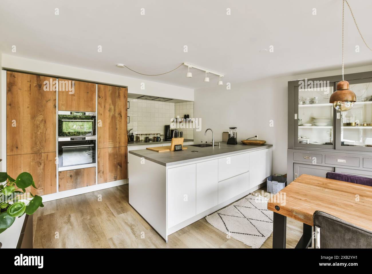 Eine stilvolle, moderne Küche mit rustikalen Holzelementen und modernem Design, mit zentraler Insel, weißen Arbeitsflächen und Tastef Stockfoto