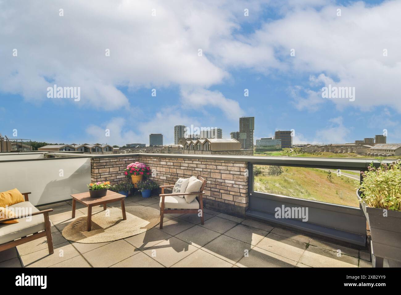 Genießen Sie den atemberaubenden Blick auf die geschäftige Skyline der Stadt von dieser gemütlichen Dachterrasse, die in einem einladenden Layout mit stilvollen Außenmöbeln präsentiert wird Stockfoto