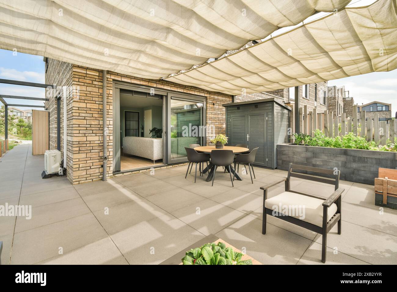 Diese einladende Außenterrasse in der Duintopstraat ist modern eingerichtet, darunter ein Esstisch, elegante Stühle und komfortable neutrale Farben Stockfoto