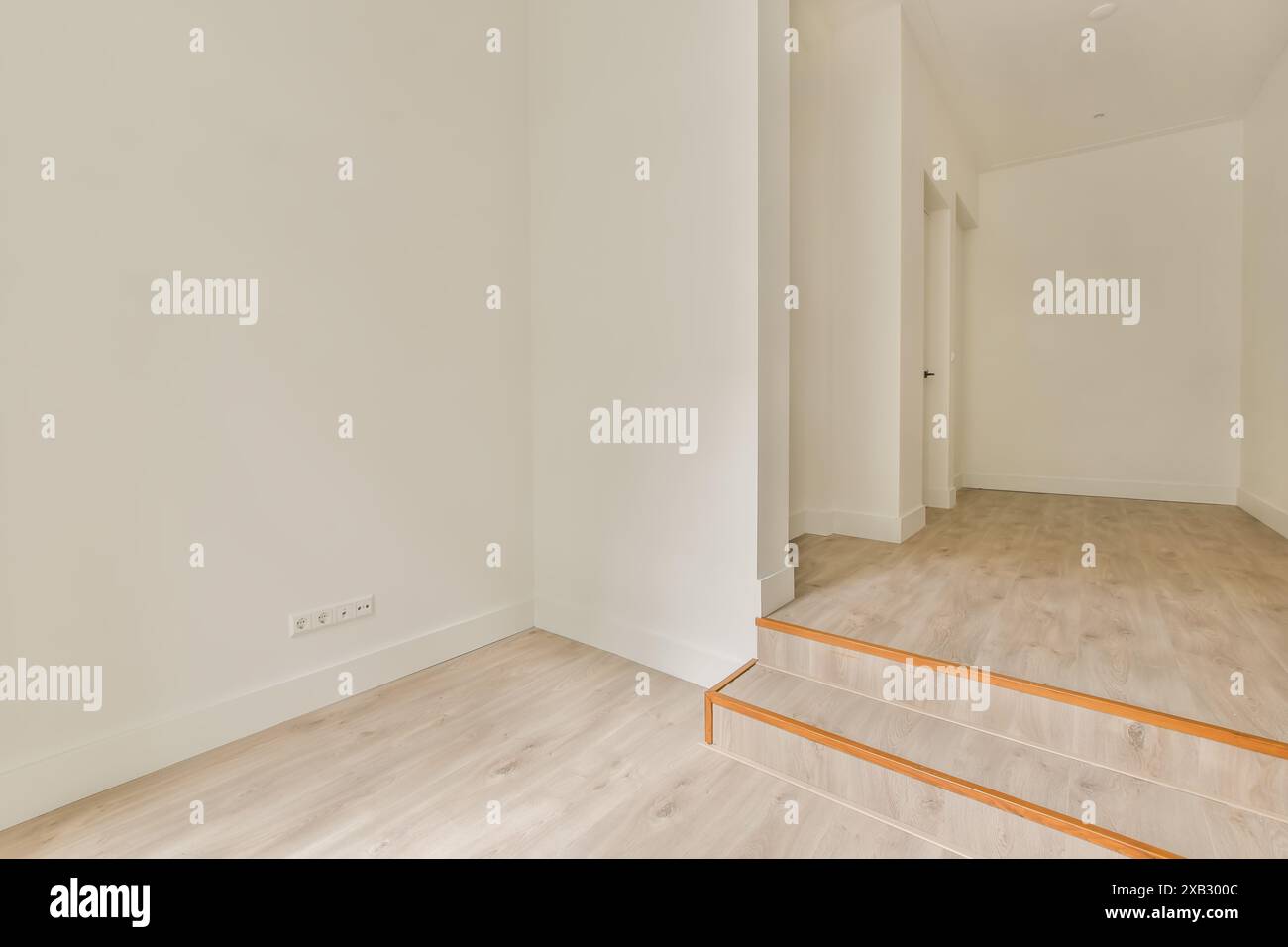 Ein minimalistisches Innendesign eines modernen Hauses mit einem leeren Raum mit neutralen Wänden und Holzböden, die durch natürliches Licht hervorgehoben werden. Stockfoto
